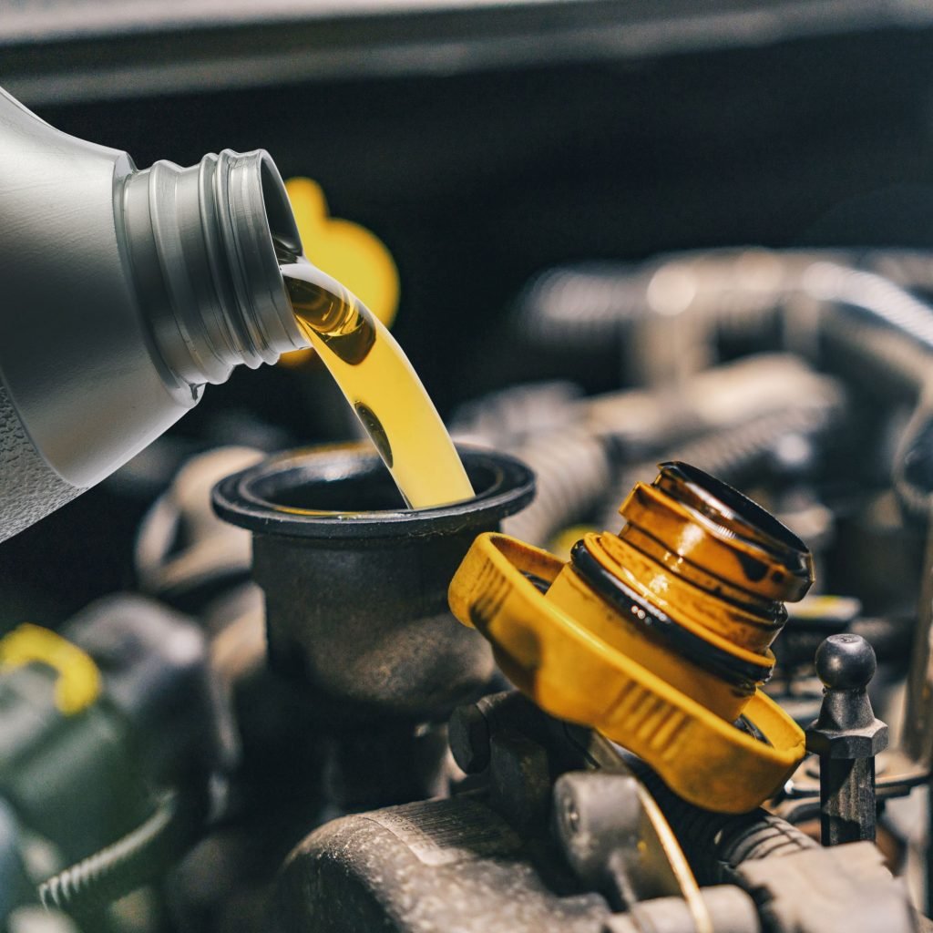 pouring oil from a container into a car engine